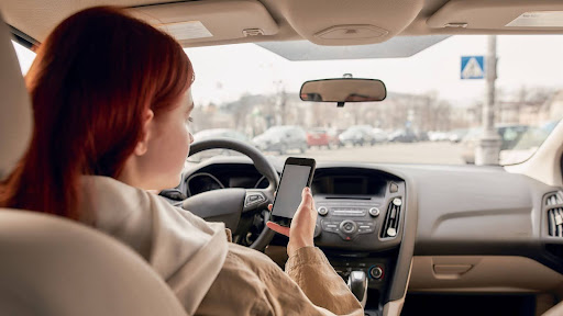 Teen using a mobile phone while driving. Texting and driving laws in Pennsylvania may constitute a form of negligence.
