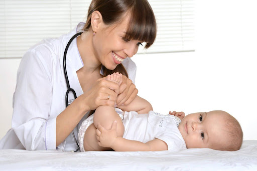 A smiling doctor examines a baby for possible birth injuries, a form of medical malpractice.