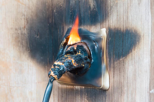 A plug from an appliance burned and melted in a wall socket, a likely cause of a product liability case.
