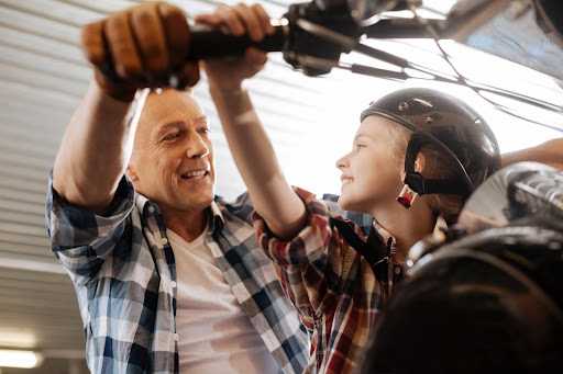 A father and his son riding a motorcycle; child motorcycle laws may impact when a child can ride with a parent.