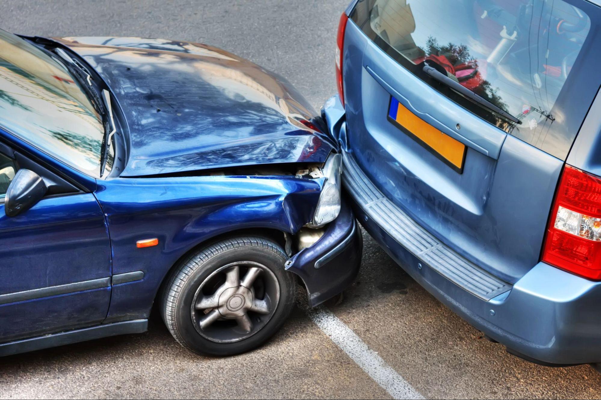 A sedan and a minivan sit idle after an unexpected rear-end accident; a car accident lawyer can help navigate the aftermath of such an accident