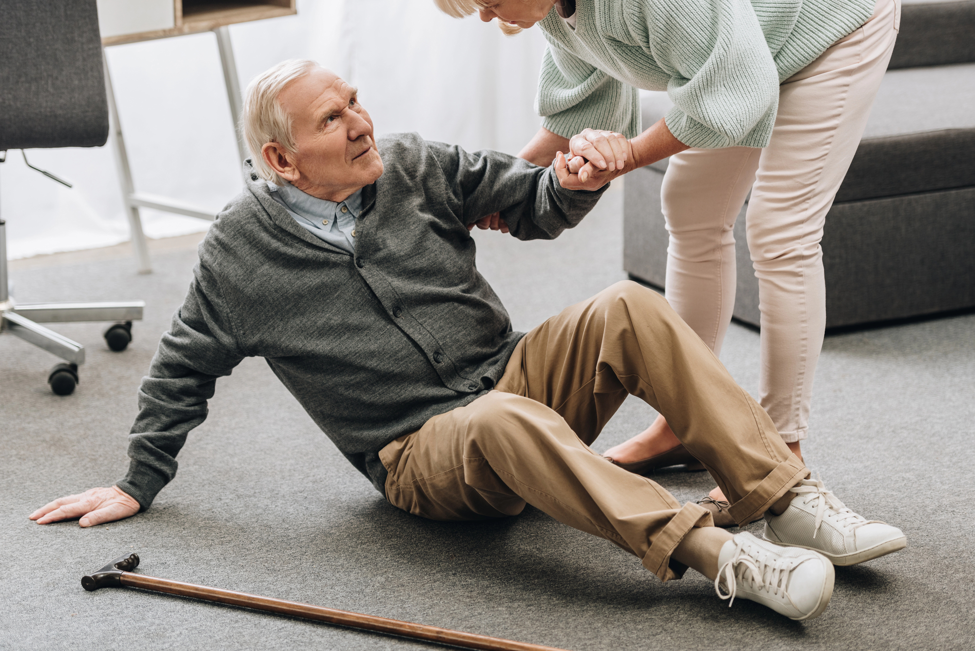 An elderly man being helped back up after a slip and fall accident.