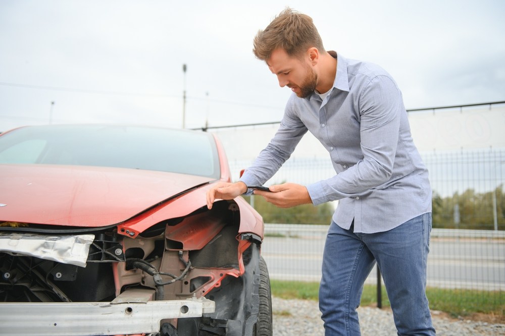 Man photographing front-end damage on his car after a car accident in Philadelphia