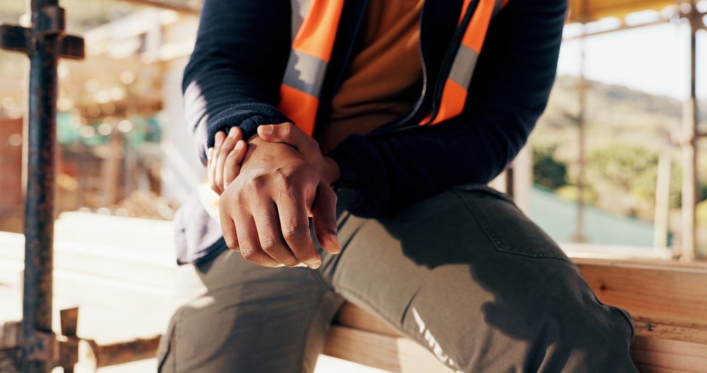 Construction worker in a safety vest sitting with clasped hands after an injury on a Philadelphia job site