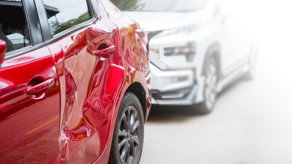Close-up of a dented red car door next to a white SUV after a collision